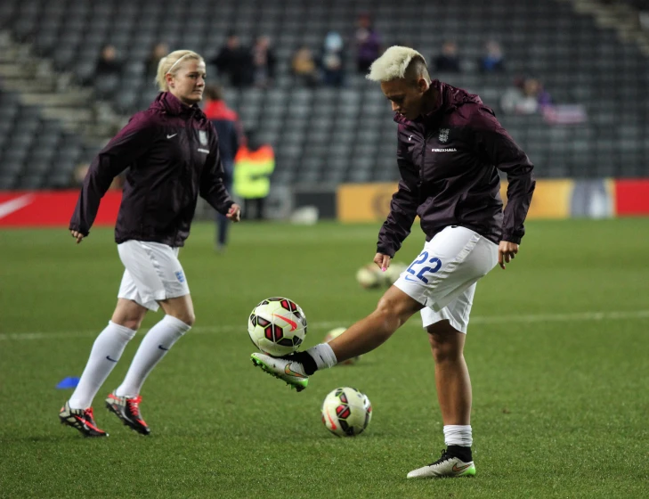 two soccer players on the field, kicking the ball