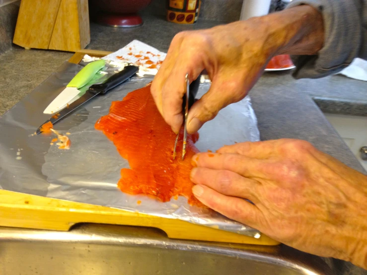 a person chopping up some fish on tin foil