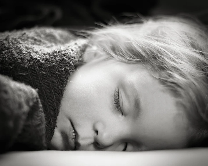 a boy sleeps with his eyes closed on a blanket