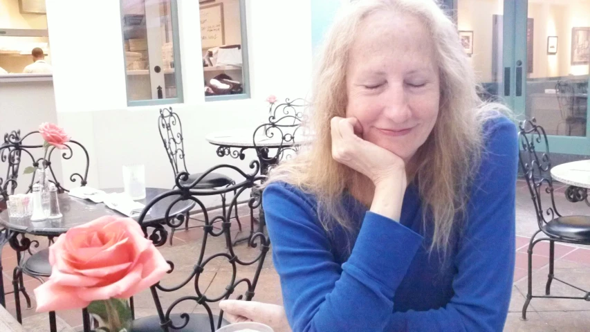 a lady sits at an outdoor table with her eyes closed