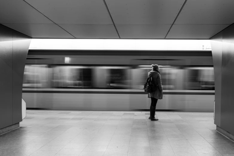 man standing in an empty subway station with one person behind him