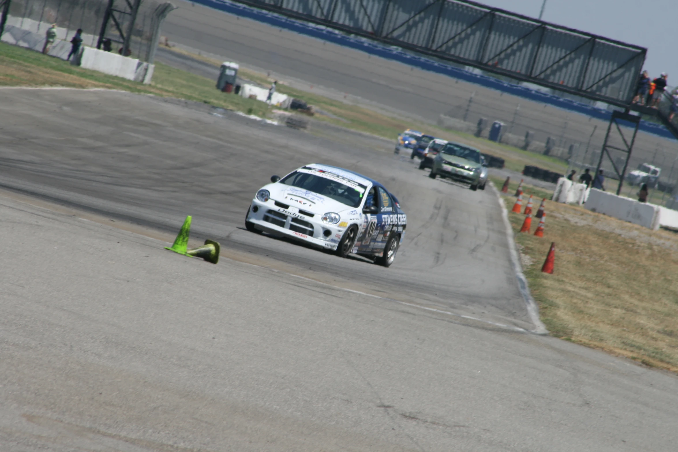 two cars racing around a track with green cones