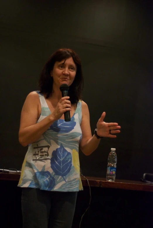 a woman stands with a microphone up to her ear