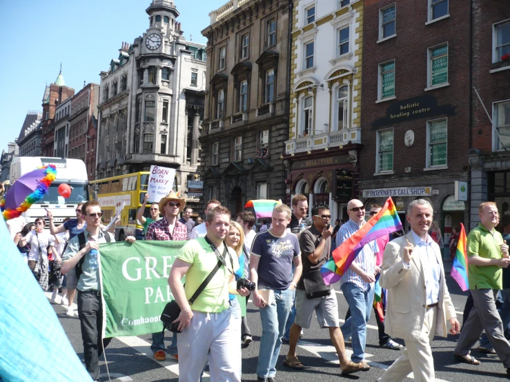 a group of people walking in a street holding up rainbow flags