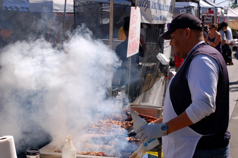 a man cooking  dogs over an open grill