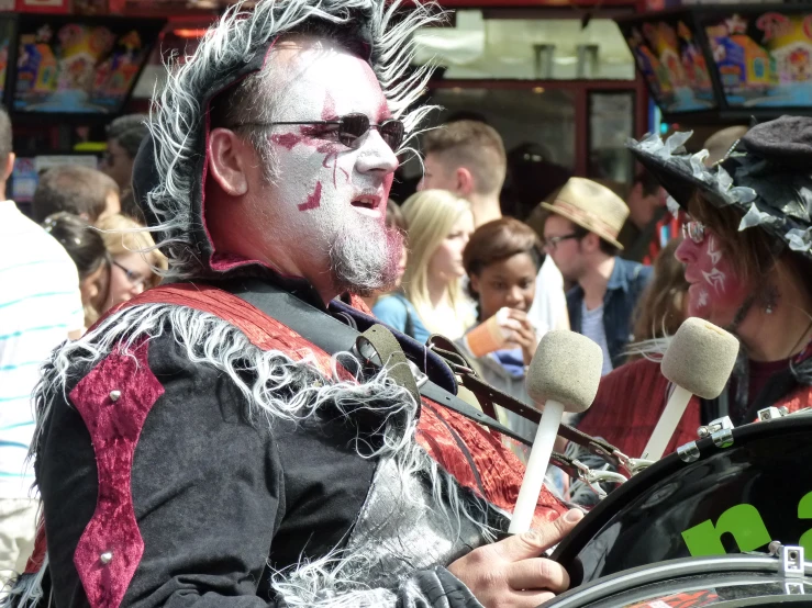 a man wearing a clown makeup is talking to the crowd