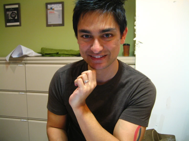 a young man smiles in a very messy bedroom