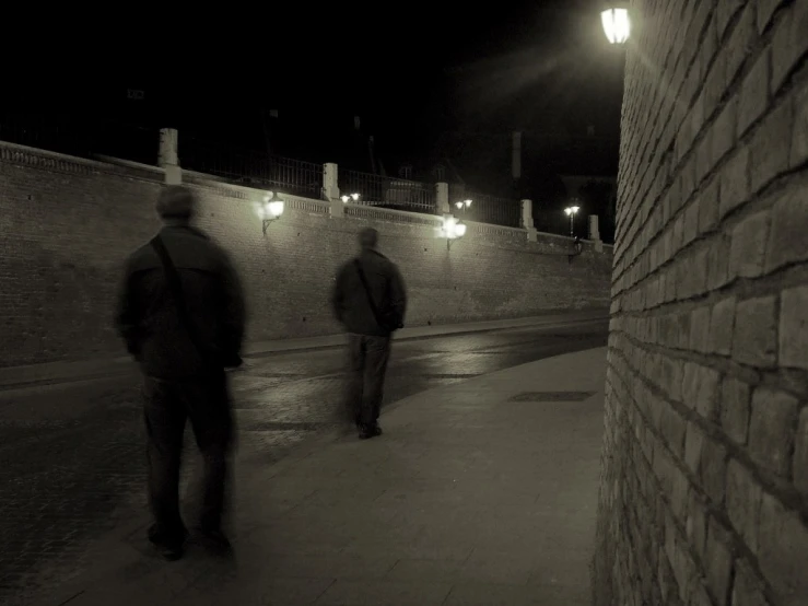 two people are walking down a street at night
