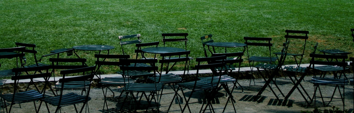 many black chairs sitting on the grass with their backs turned to one another