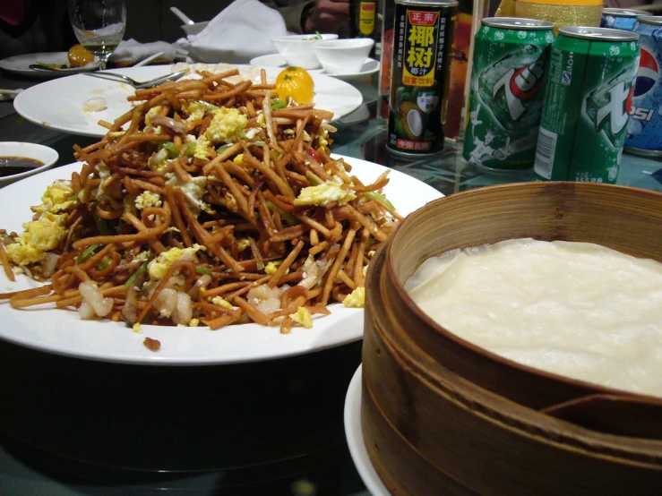 a white plate topped with meat covered in broth next to a container filled with milk and rice