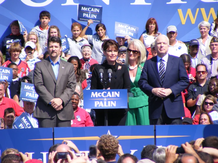 a man and woman speaking on stage at a campaign