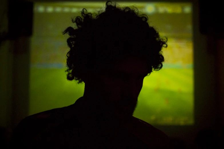 a dark background with a blurry image of a guy and the tv is behind him
