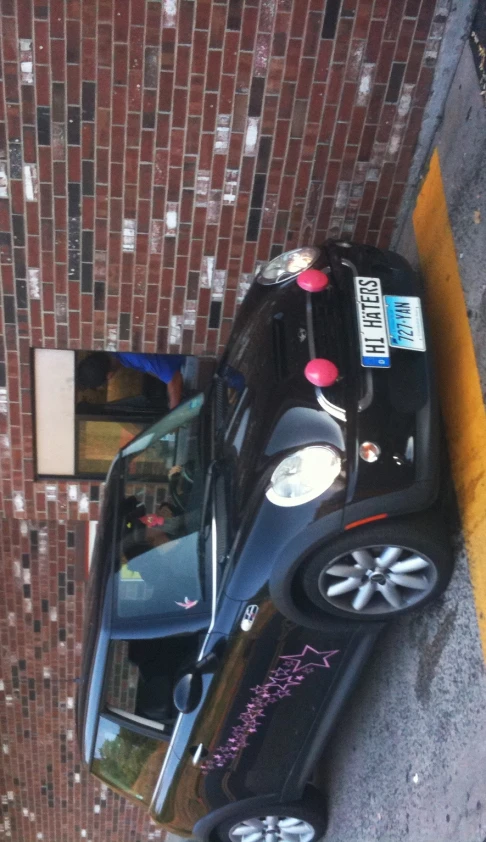 mini hatch with a custom sticker in front of brick building