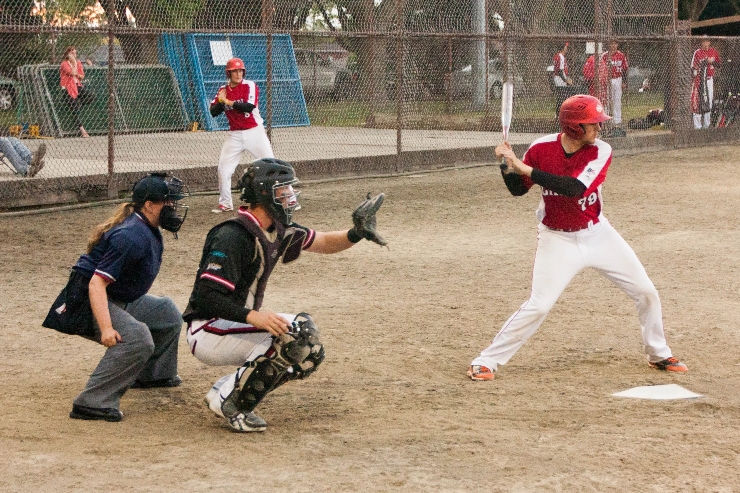 the batter stands ready to hit the ball while the catcher waits for the ball