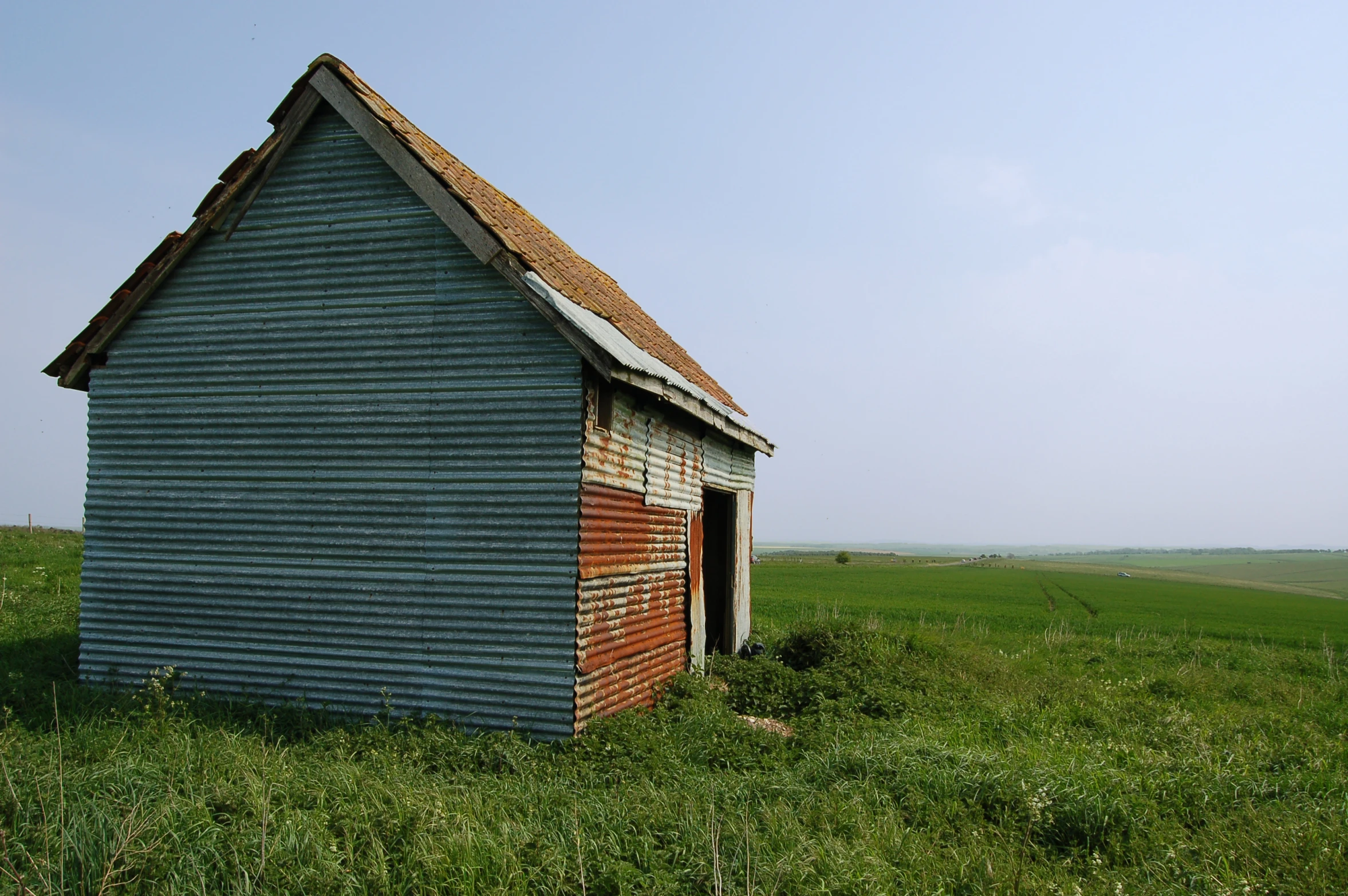 an old, worn down shed sits in a field