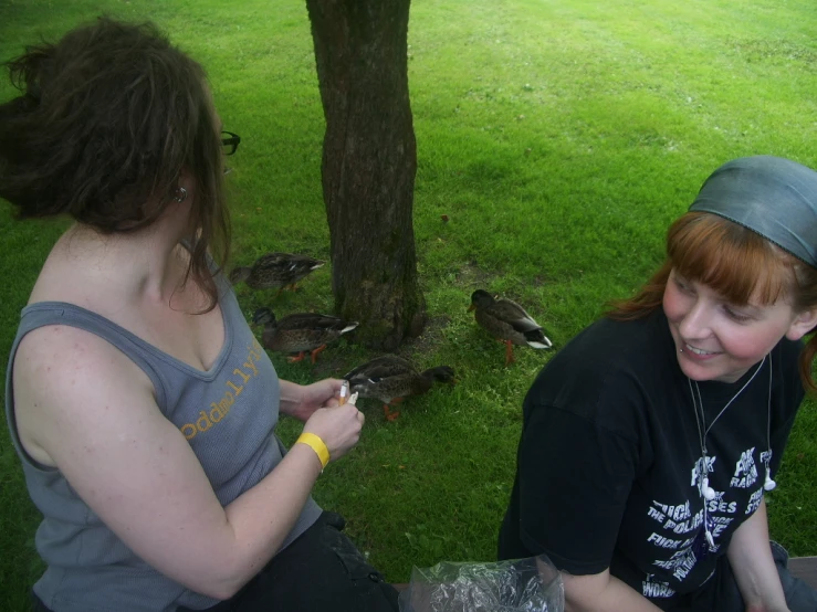 two women talking to each other near some birds