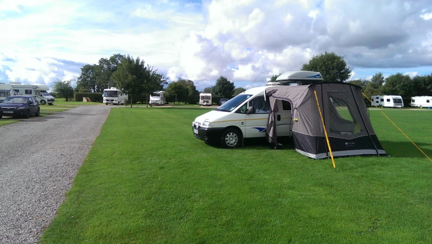 an rv in a grassy field with tents