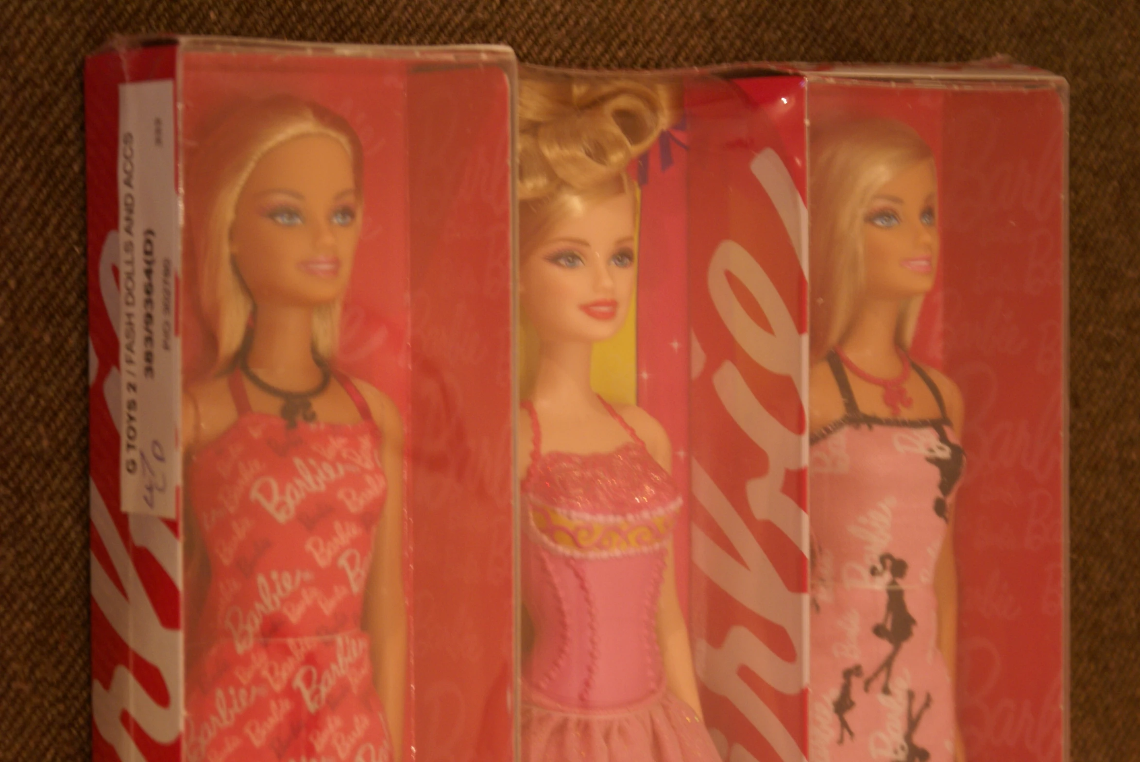 three barbie dolls in plastic packaging one in the middle of the other