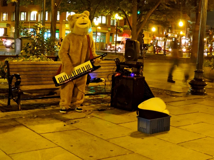 the mascot is holding an instrument and sitting on a park bench