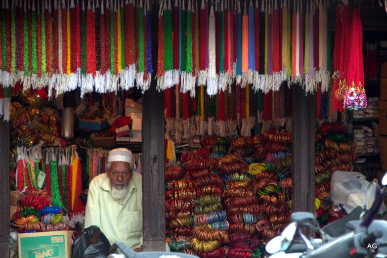 a man sits in front of colorful string store