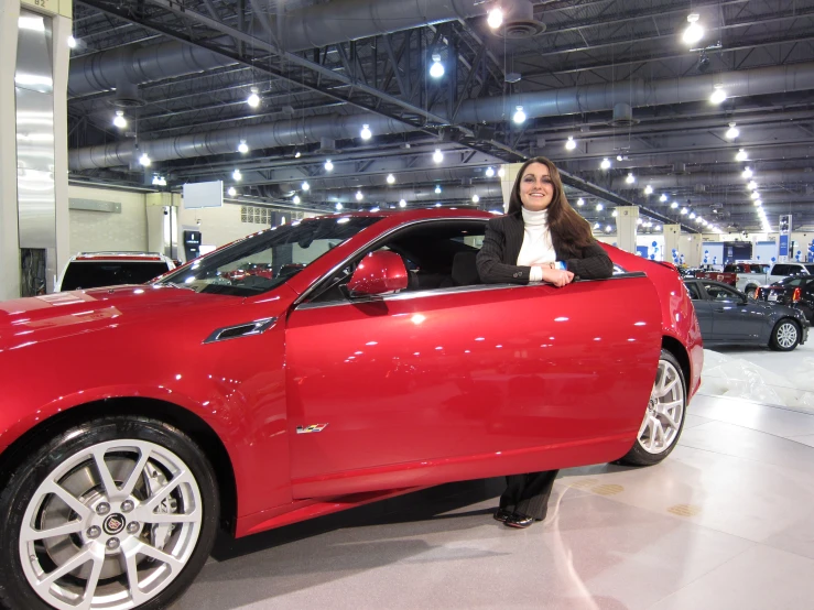 a woman is standing behind a red car