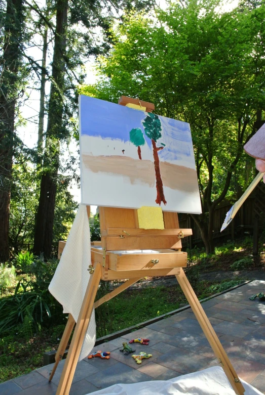 a wooden easel with paintings displayed on it in the park