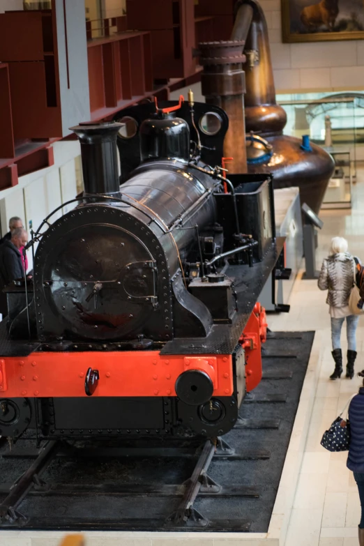 two people near a black locomotive in a museum