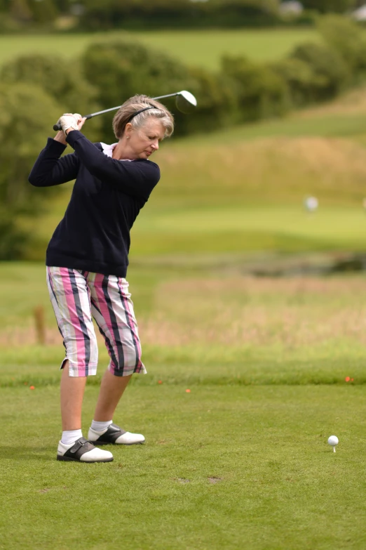 a woman holding a golf club while wearing a black top