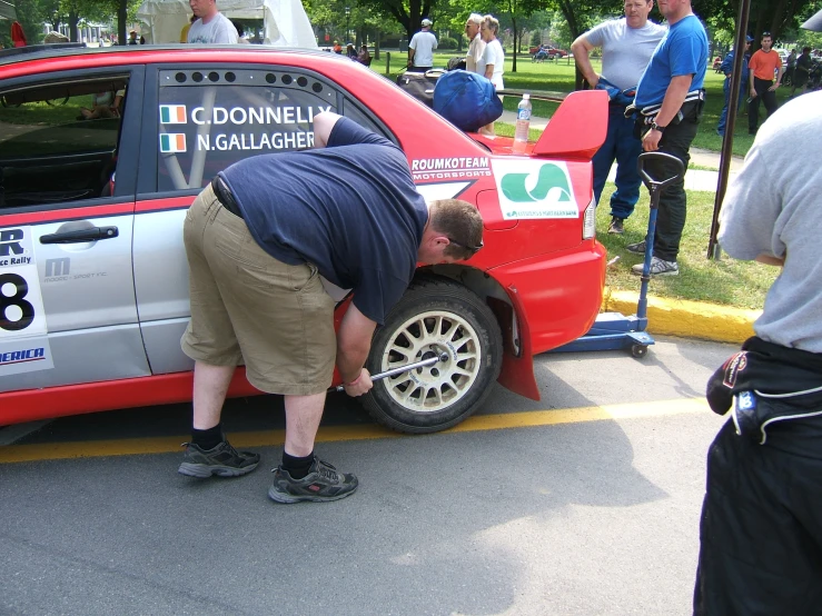 a man fixing the side fender on a car