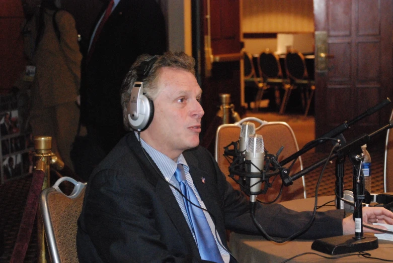 a man wearing headphones sits at a microphone