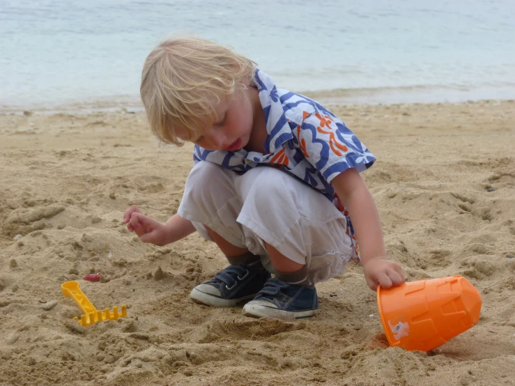  playing with orange plastic toy on sand beach