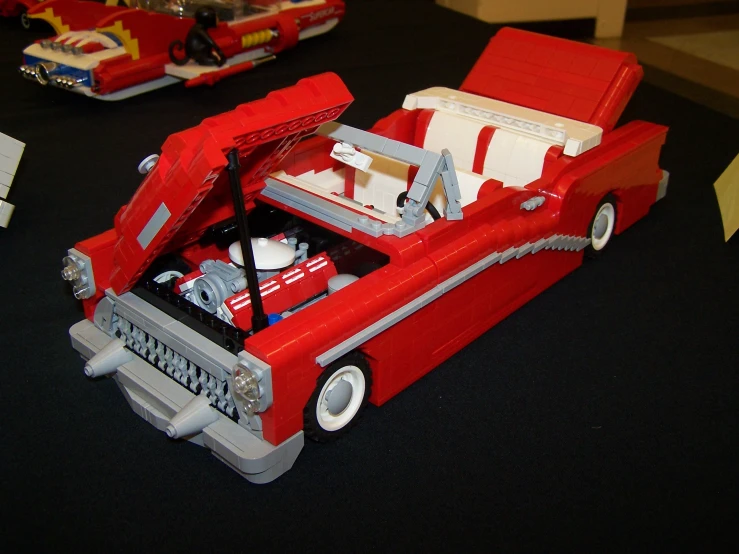 a toy car with an open fire hose in it and other toys nearby