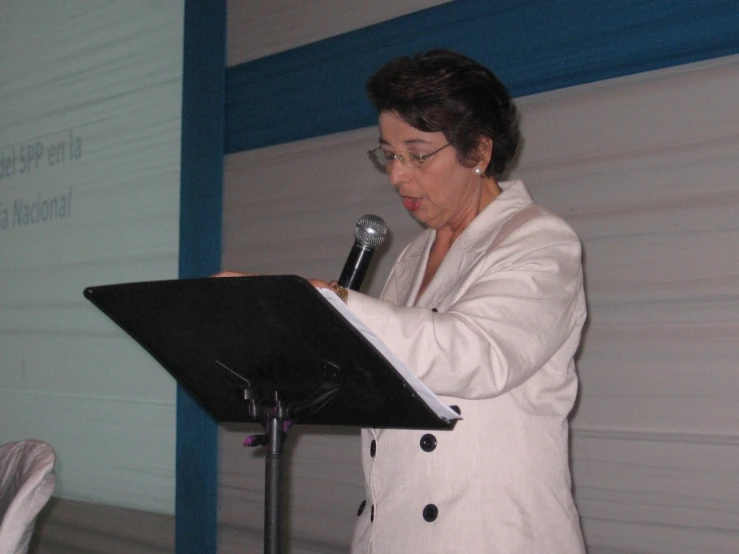 an older woman holding a microphone and giving a speech