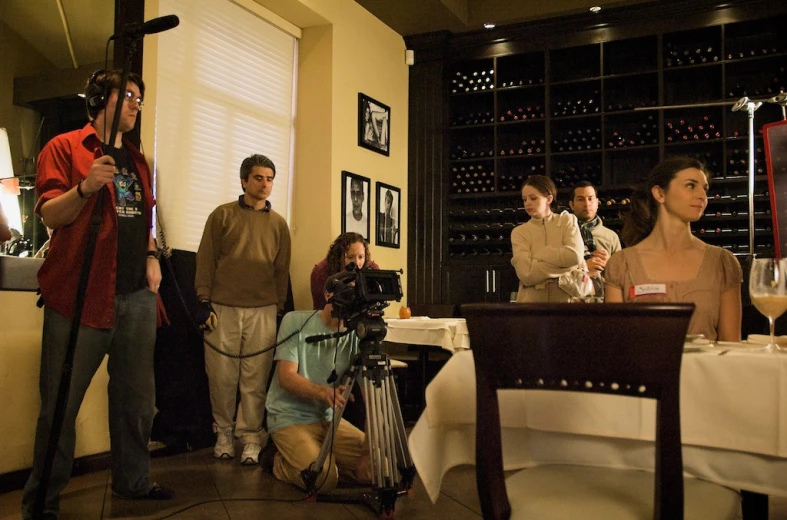 people in a wine shop with a camera filming the event