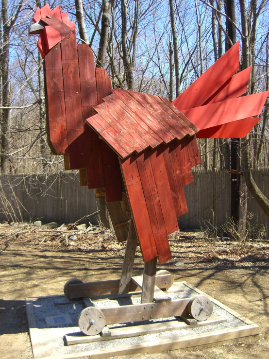the wooden sculpture depicts a red rooster that appears to be made of wood