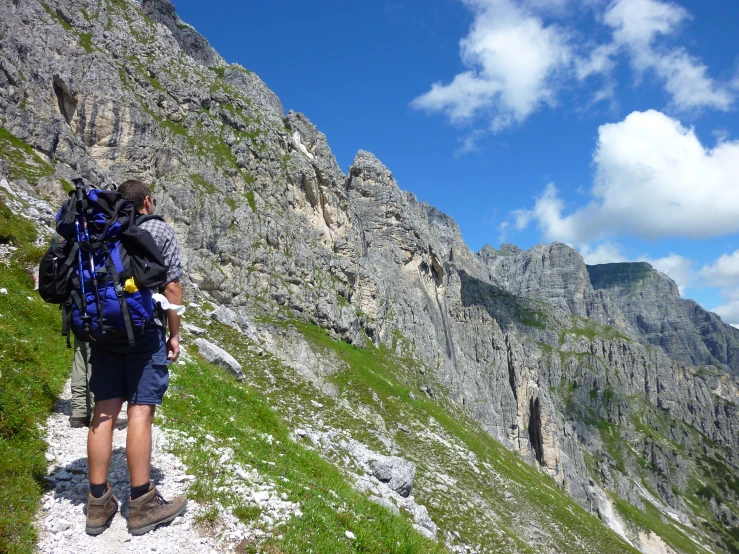 man hiking up side of mountain in a blue backpack