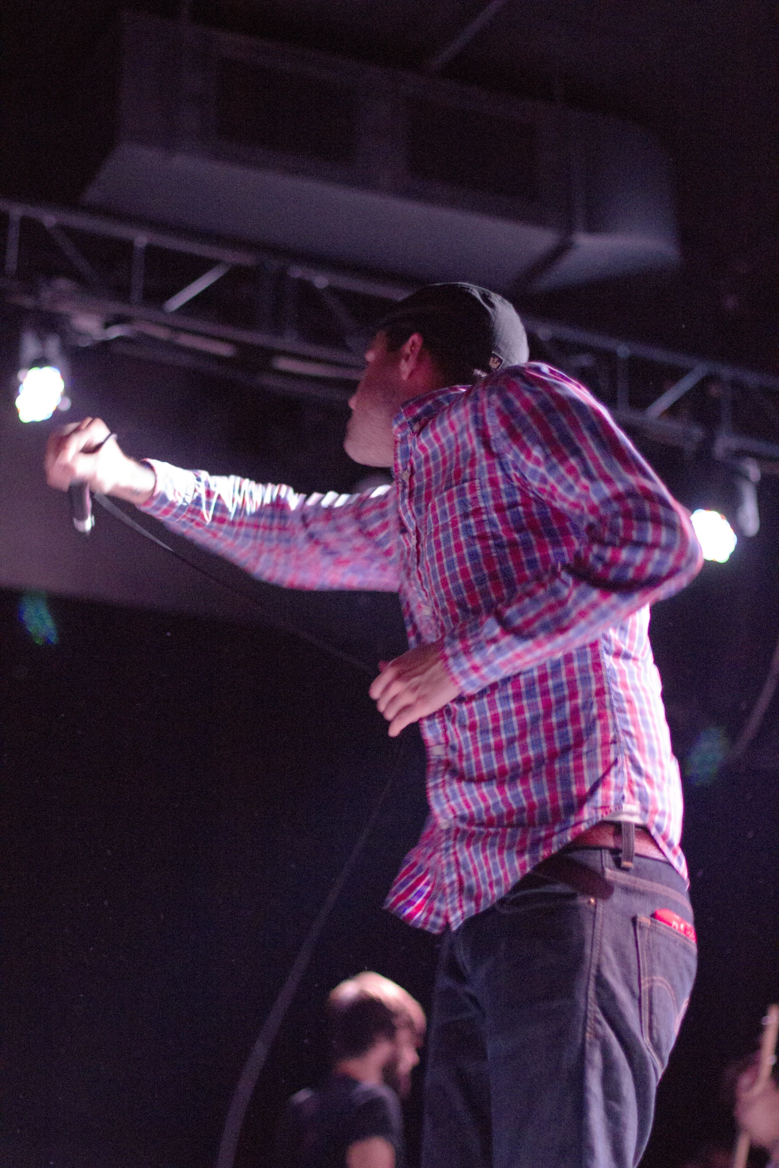 a man wearing a cap holds his hands out to another person who is on stage