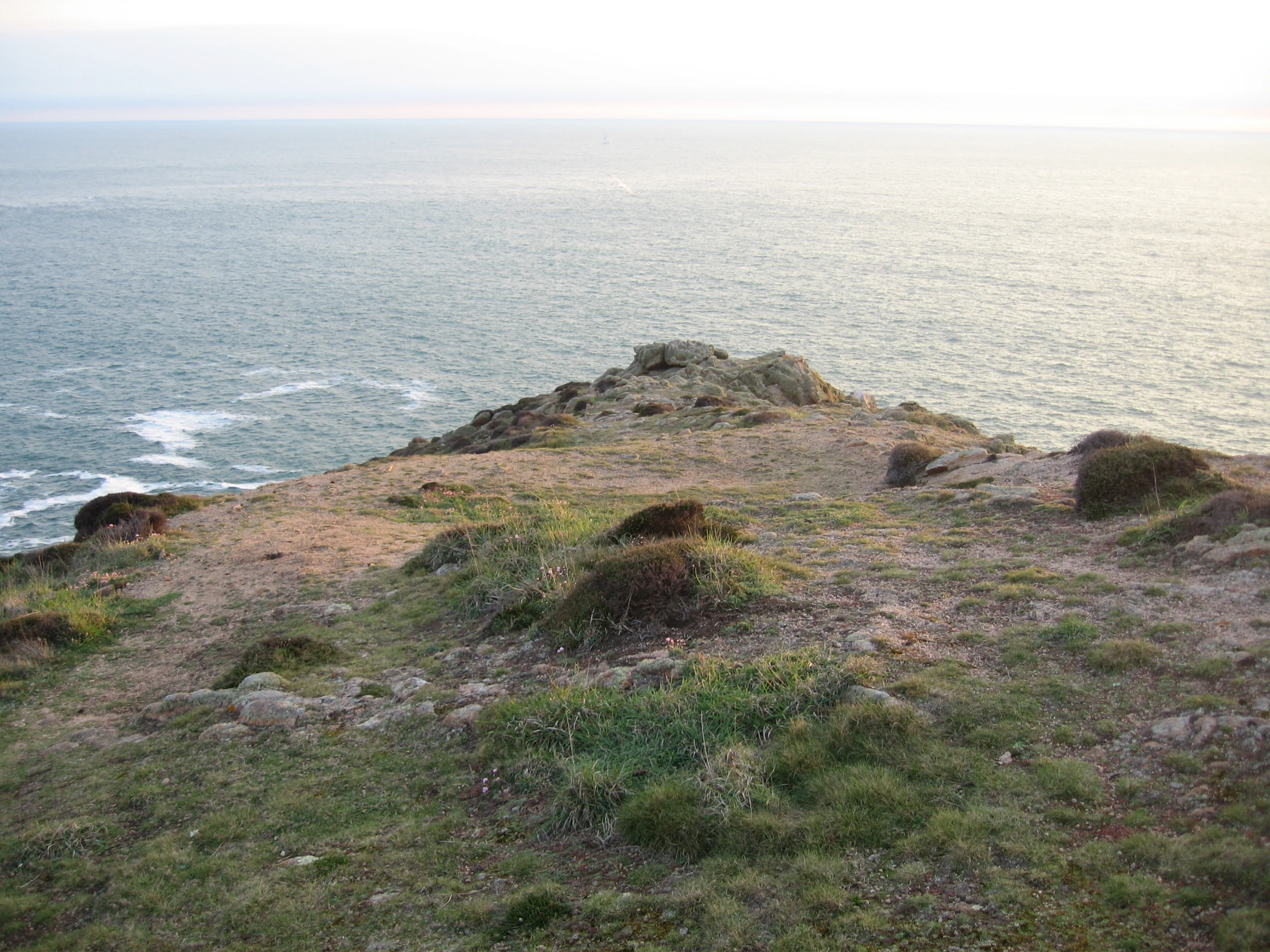 a grassy area near the water and a rock face