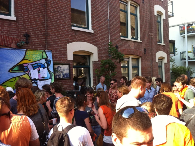 a large crowd stands in front of brick building