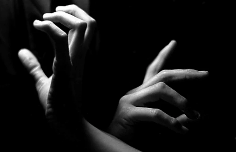 two hands reaching towards each other in the dark
