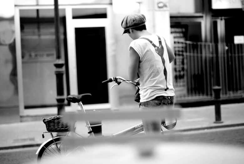 a man in white shirt and shorts standing by a bike