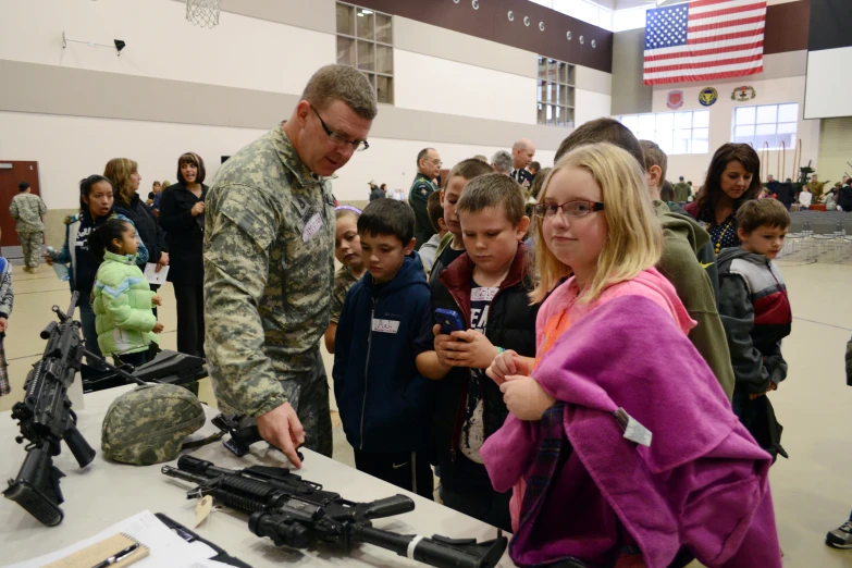 a soldier looking at a cell phone with children