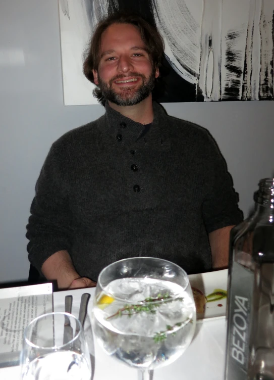 a man sitting at a table with two drinks