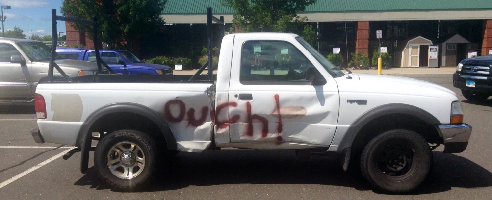 a white pickup truck with graffiti written on the front in a parking lot