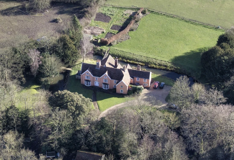 an aerial view of a two story home surrounded by lush green countryside