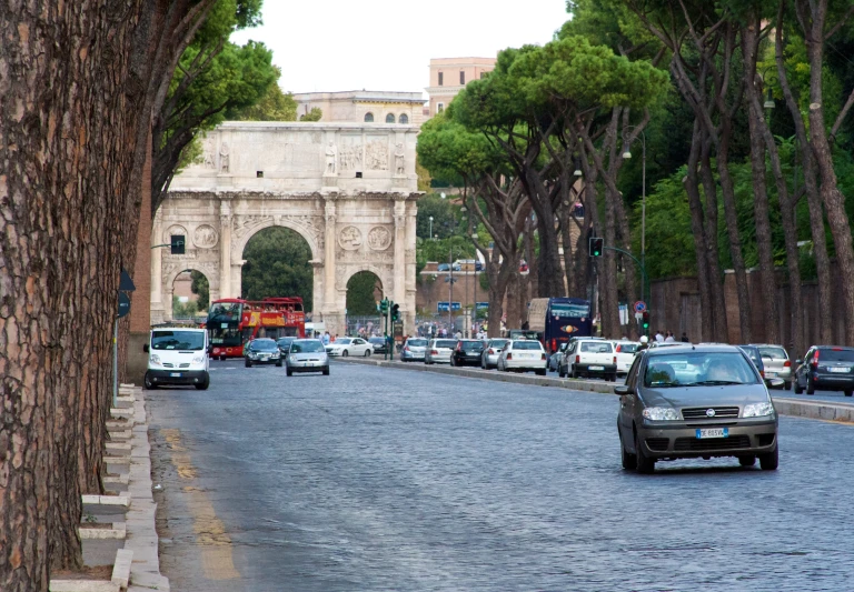 a street with cars passing by and traffic going under an arch