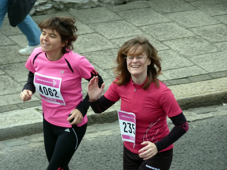 two women running together, one with her hand in the air