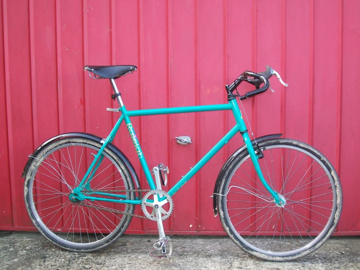 a blue bike is against a bright red wall