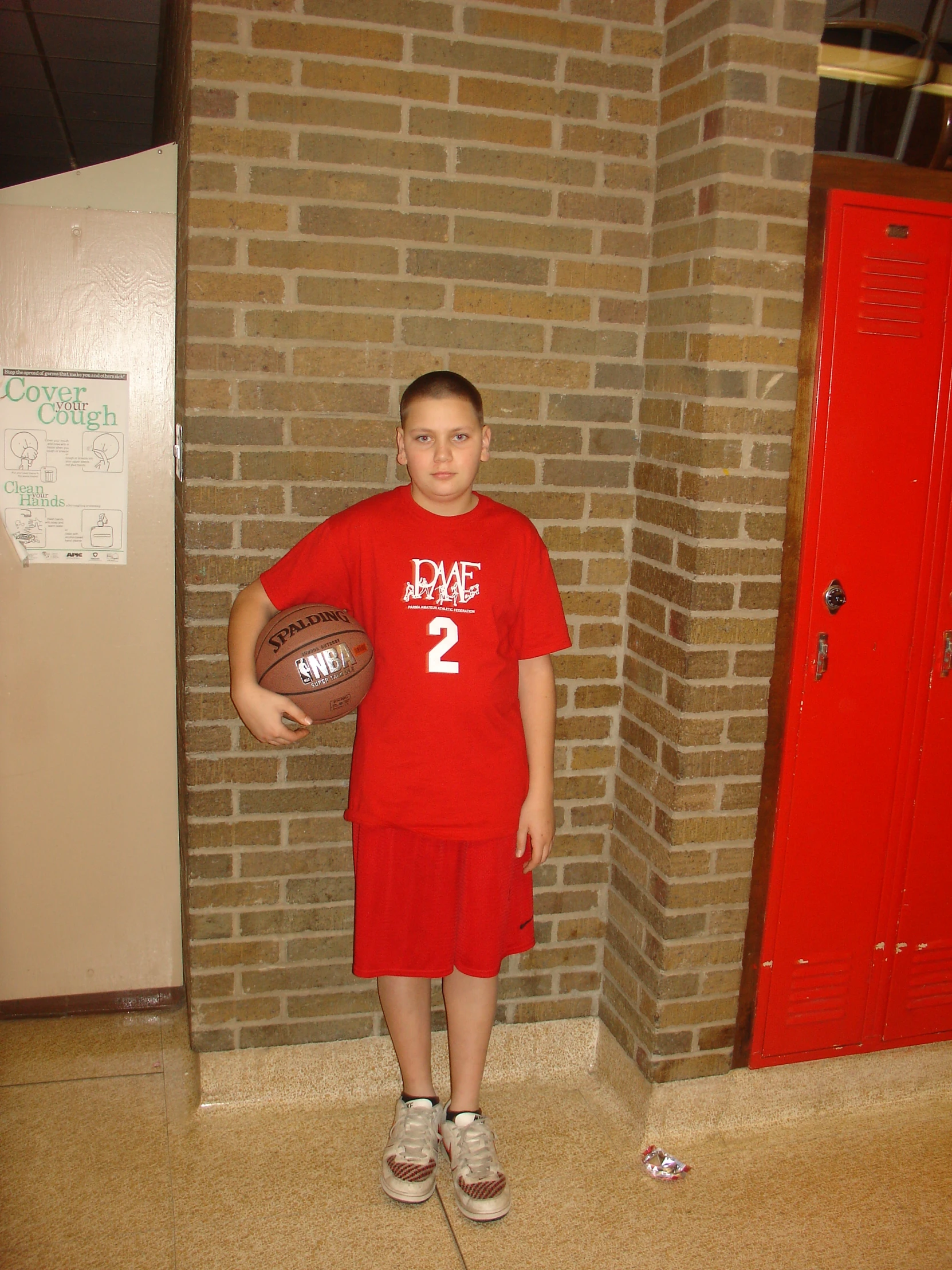 a little boy that is standing in front of a brick wall