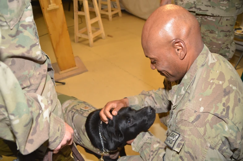 a man in uniform petting a dog that is being held by another person